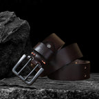 Echtleder-Gürtel aus braunem Rindsleder auf schwarzem Steinfelsen – aufgerollte Seitenansicht