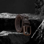 Echtleder-Gürtel aus dunklem Rindsleder auf schwarzem Steinfelsen – Seitenansicht mit Metallschnalle