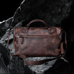 Echtleder Umhängetasche mit Überschlag – Detailansicht auf schwarzem Steinfelsen