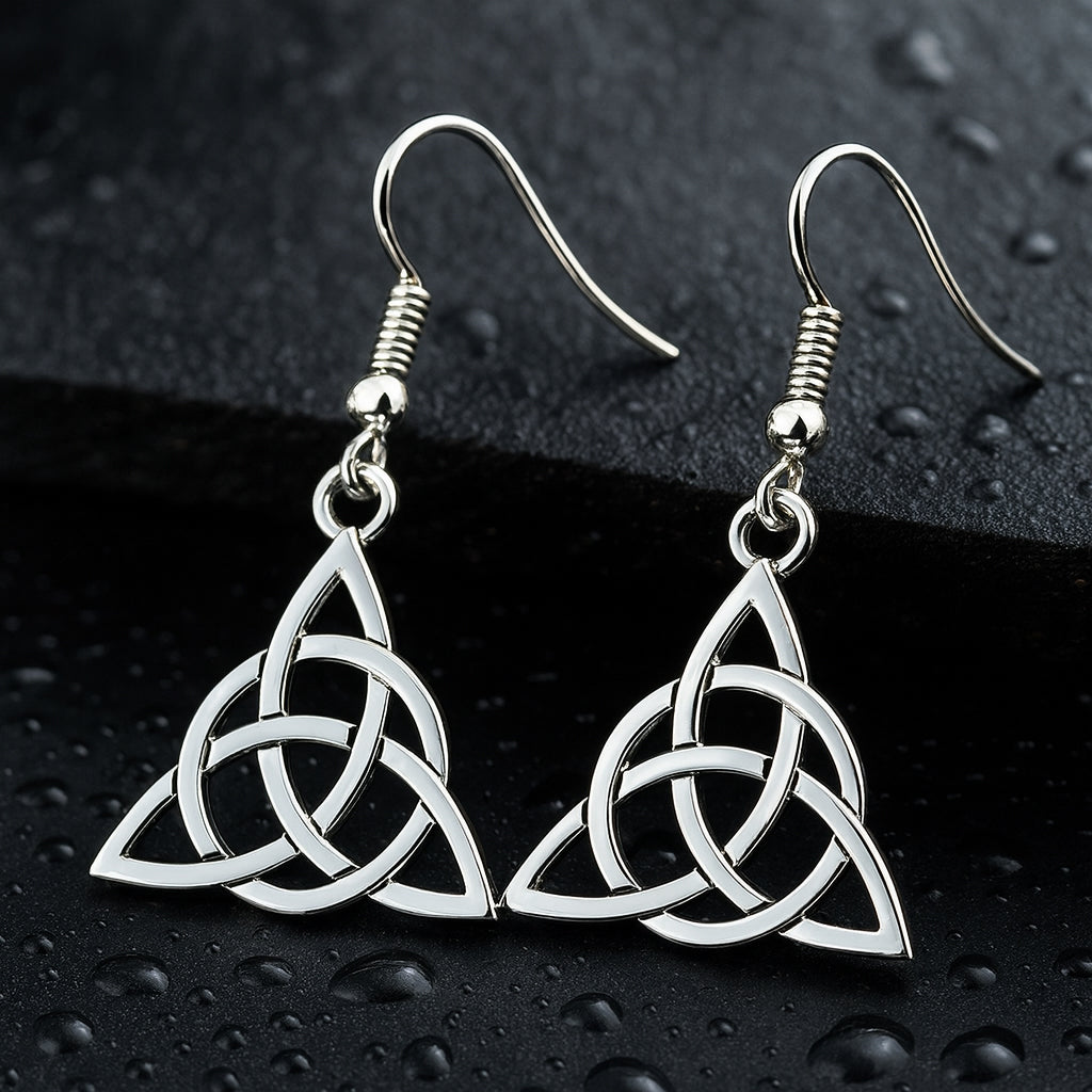 Hochglanzpolierte Triquetra Ohrringe aus Edelstahl auf nassem, dunklem Granit.