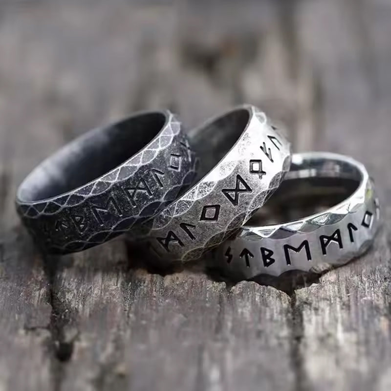 Echte Wikinger Ringe aus Edelstahl – drei FUTHARK Runenringe mit gravierten Symbolen der nordischen Mythologie, liegend auf Holz.