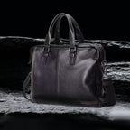 Herren Echtleder Tasche schwarz, hochwertige Business Ledertasche aus echtem Leder auf schwarzem Felsen frontal