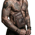 Nordische Smartphone Umhängetasche mit Rabenmotiv aus Kunstleder getragen von tätowiertem Wikinger-Model als kompakte Handytasche mit Schultergurt für Alltag und Reisen